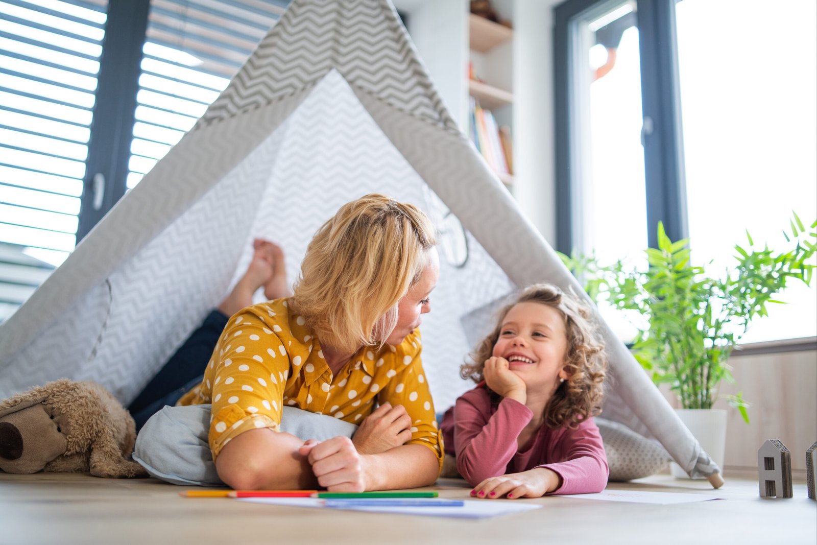 A cute small girl with mother indoors at home, playing.